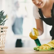 Close-up on housewife with yellow gloves and cloth cleaning a table at home Close-up on housewife with yellow gloves and cloth cleaning a table at home